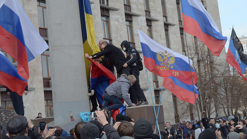 Pro-Russian protesters remove a Ukrainian flag and replace it with a Russian flag in front of the Donetsk Oblast Regional State Administration building in March 2014 (credit: wikimedia commons)