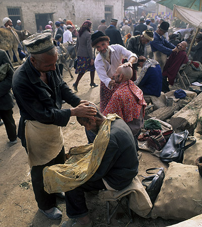 Street barbers, from the Uygur ethnic group, at work in the Kashgar bazaar in Xinjiang, China - 1991 (Pic: UN Photos)