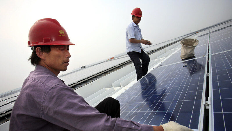 workers install solar panels on a rooftop