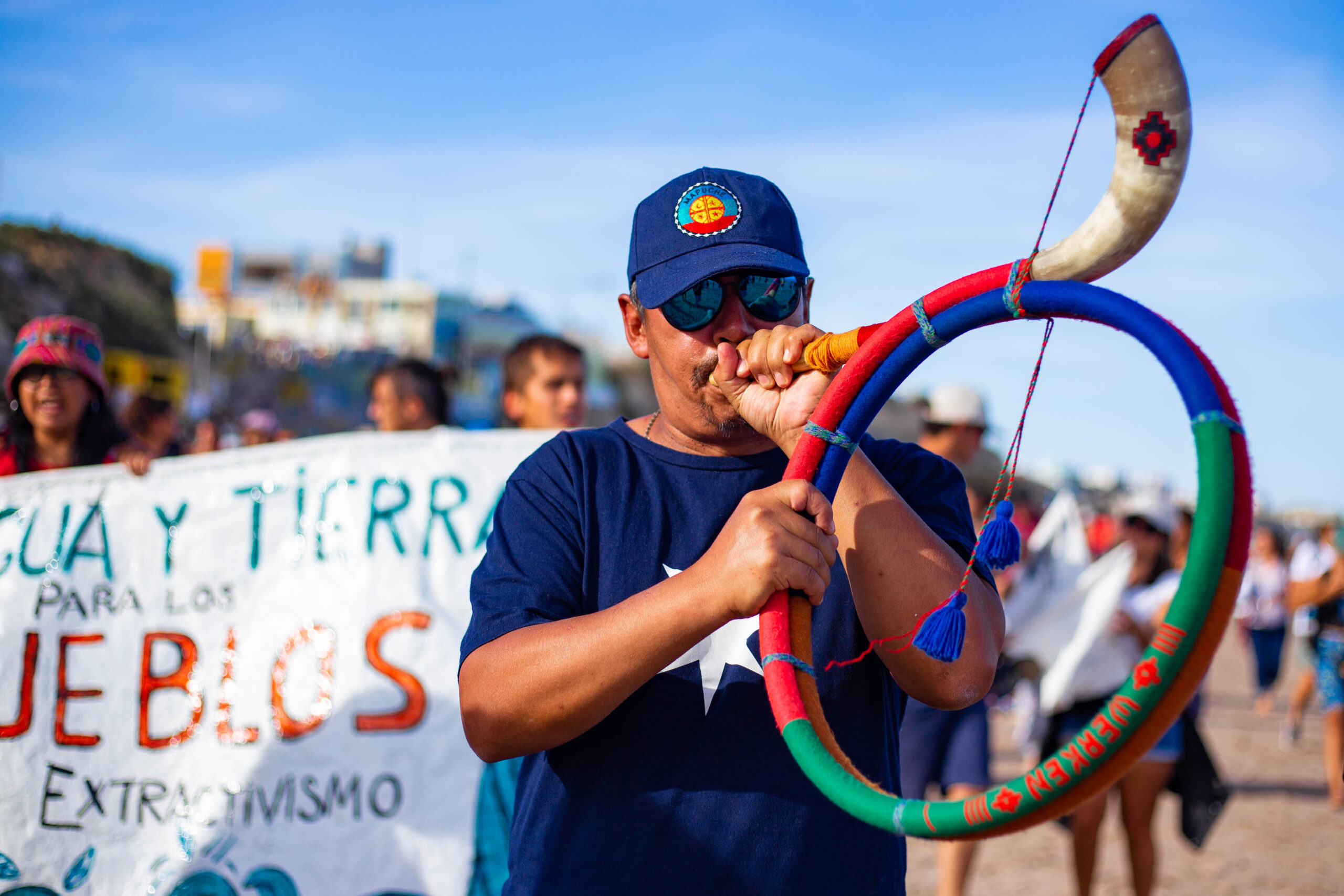 A mapuche activist blowing a horn-like instrument at a demonstration against the Vaca Muerta Sur LNG terminal. Argentina is pushing a major oil and gas exporting terminal