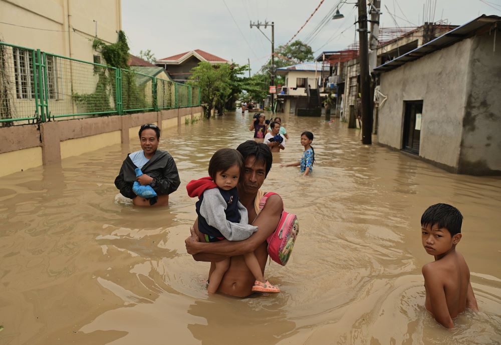 People wade through a flooded street caused by continuous rain brought by Typhoon Yagi, in San Miguel, Calumet, Bulacan, north of Manila, Philippines, on September 3, 2024.