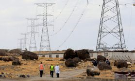 Workers walk near power lines connecting pylons of high-tension electricity from the power substation at the Lake Turkana Wind Power project (LTWP) in Loiyangalani district, Marsabit County, northern Kenya, September 4, 2018. African leaders seek investments to achieve energy goals