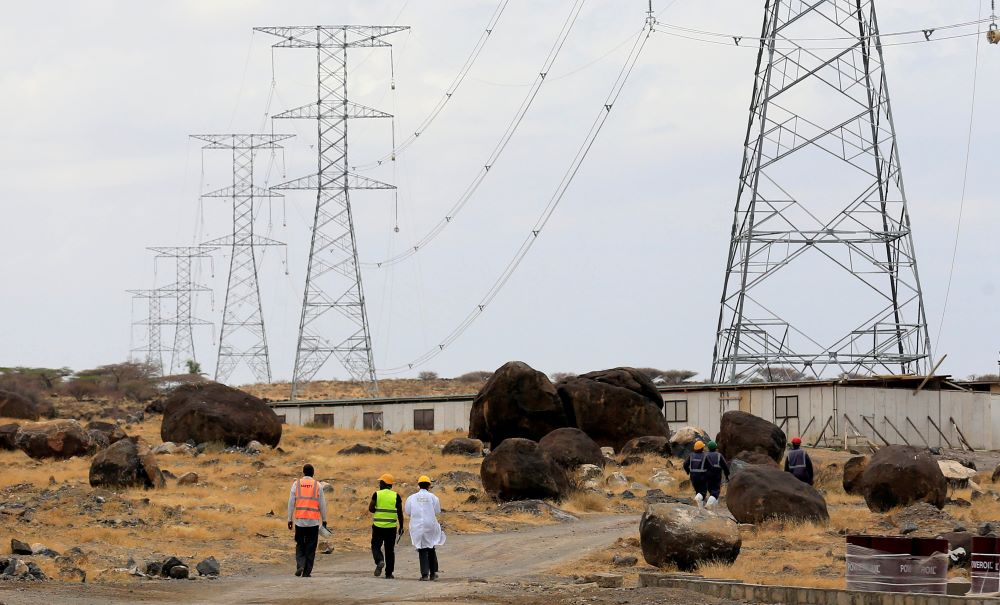 Workers walk near power lines connecting pylons of high-tension electricity from the power substation at the Lake Turkana Wind Power project (LTWP) in Loiyangalani district, Marsabit County, northern Kenya, September 4, 2018. African leaders seek investments to achieve energy goals